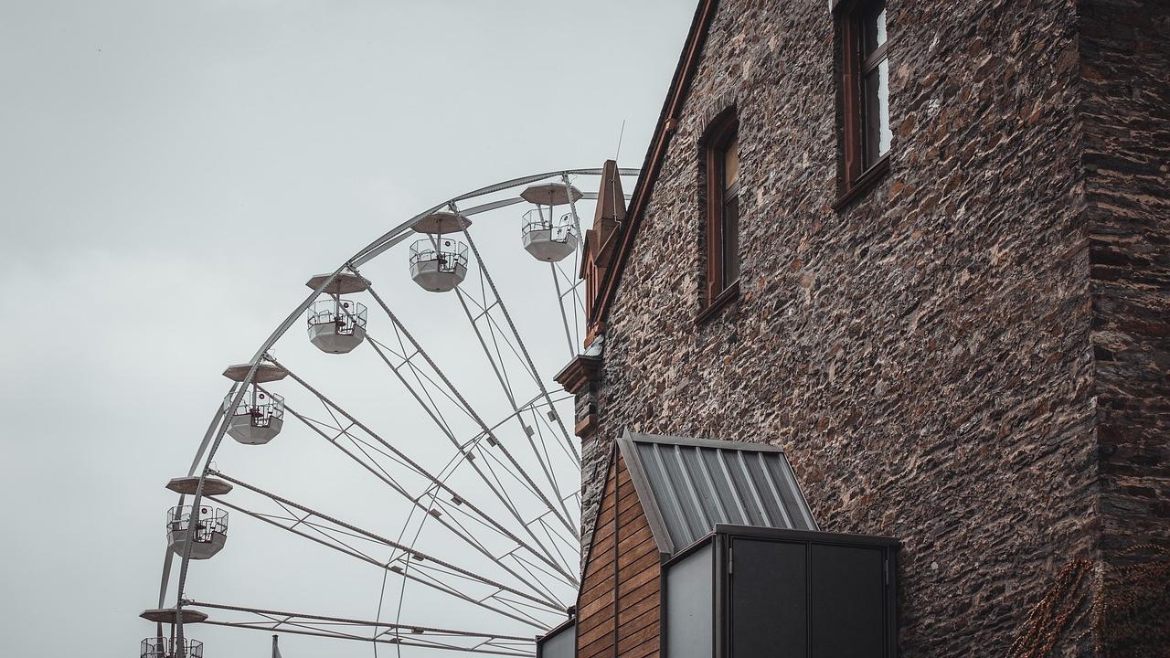 Ferris wheel, partially hidden behind old brick building