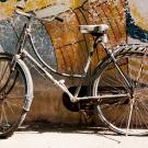 old white bicycle leaning against wall with faded mural