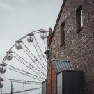 Ferris wheel, partially hidden behind old brick building