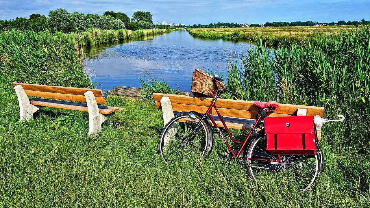 Bicycle parked next to bench near stream