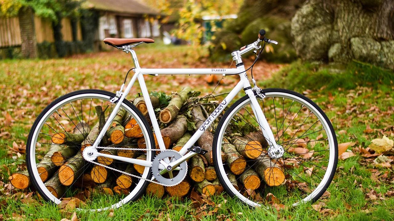 White bicycle leaning against stack of wood