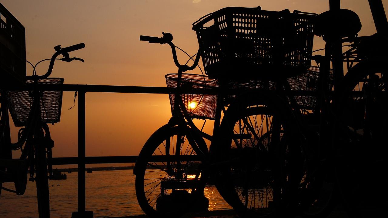 Bicycles leaning against railing with sunset in the background