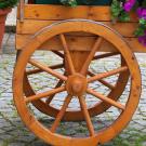 Pink flowers in wooden cart with large wheel