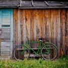 Green bicycle leaning against rustic shed