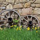wooden wagon wheels leaning against stone wall